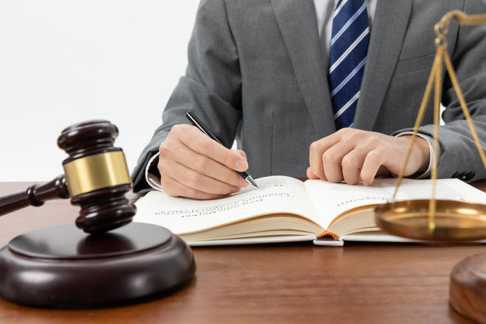A lawyer writing in a book with a gavel on the table