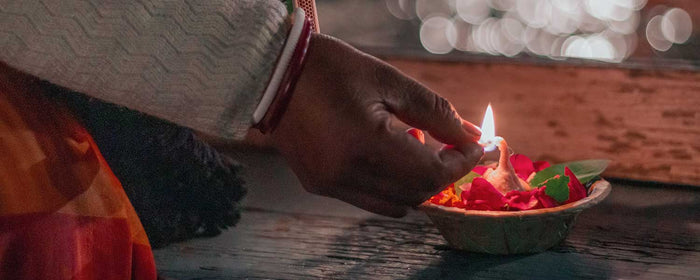 A man lights the wick of an aarti